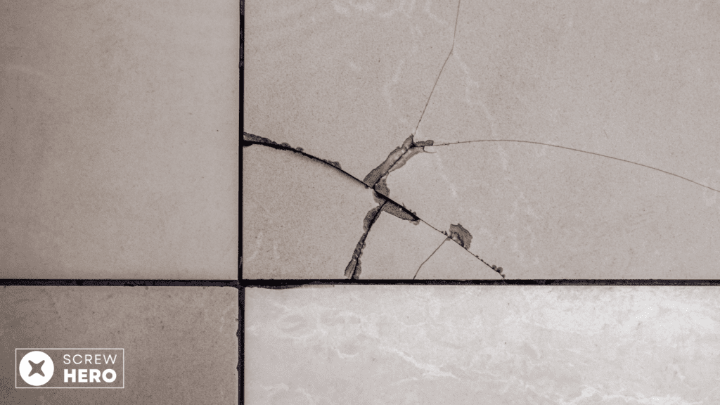 Removing a cracked tile with a chisel and hammer.