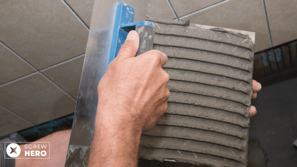 Spreading tile adhesive with a notched trowel.