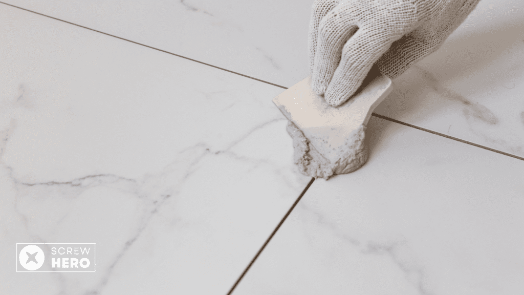 Applying grout to the repaired tile using a grout float.